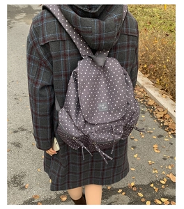 Outdoor shot of a grey nylon star pattern backpack with multiple zipper pockets