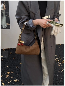 Fashionable brown suede hobo bag with red cherry charm accessory worn with casual blazer