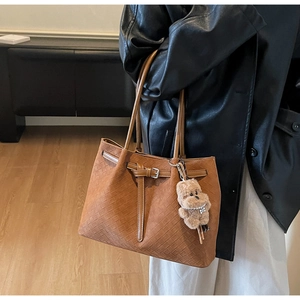 Detailaufnahme der braunen geflochtenen Tragetasche mit Plüschbär und Griffen