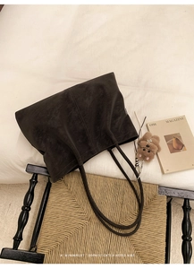 Close-up of retro matte dark tote bag with vertical stitching on a vintage chair