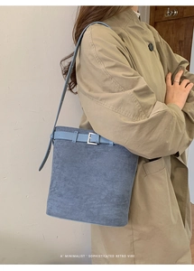 Détail du sac seau bleu mat avec boucle décorative et texture en daim raffinée