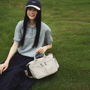 Detail of cream nylon crossbody bag with double front zippers and woven handles
