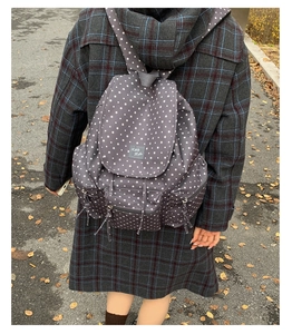 Detail of grey canvas backpack with white star pattern and drawstring closure shown on model