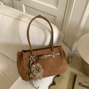 Detail of vintage brown suede tote bag with leather belt buckle and plush bear charm