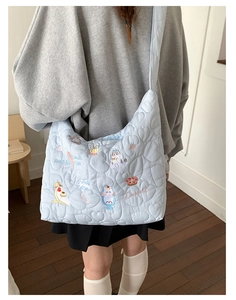 Détail d'un sac cabas matelassé bleu clair avec coutures en cœur et broderie chat
