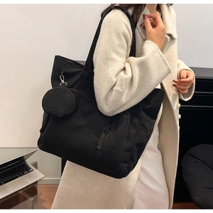 Dettaglio della borsa tote nera in velluto a coste con pochette tonda e tasca laterale