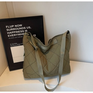 Detail of olive green quilted tote bag featuring classic diamond stitching and wide strap