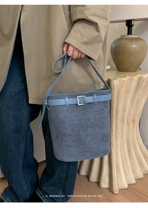 Détail du sac seau bleu Morandi montrant la texture suède et la boucle carrée argentée
