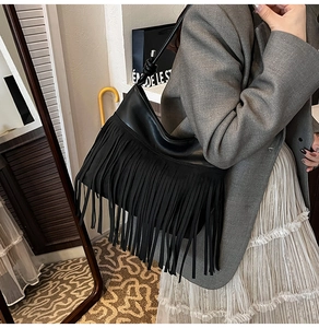 Dettaglio di una borsa a tracolla retrò con frange nere che mostra il movimento dei nappe