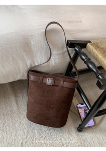 Détail d'un sac seau en daim marron foncé avec boucle carrée en métal argenté et sangle