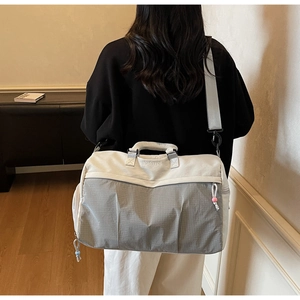 Détail du sac de voyage à carreaux montrant sa grande capacité et sa bandoulière réglable