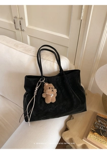 Detail of black matte retro tote bag with plush bear charm in a lifestyle interior setting