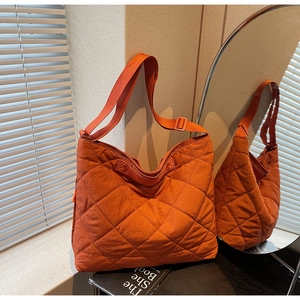 Detail of orange quilted tote bag with diamond stitching and adjustable wide shoulder strap
