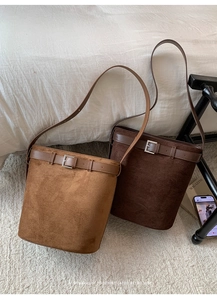Vue détaillée des sacs seaux en daim marron clair et café foncé sur un tapis minimaliste