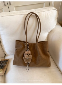 Detail of retro brown tote bag with leather texture and cute plush puppy charm pendant