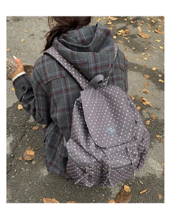 Close-up of dark grey star pattern backpack featuring multi-pocket design on casual model