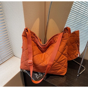 Detail of orange quilted tote bag featuring textured matte nylon and diamond stitching