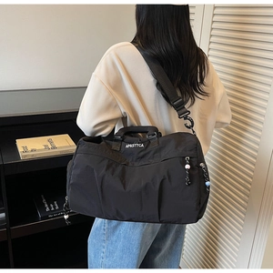 Vue arrière du mannequin portant un sac de voyage noir étanche avec lettrage blanc