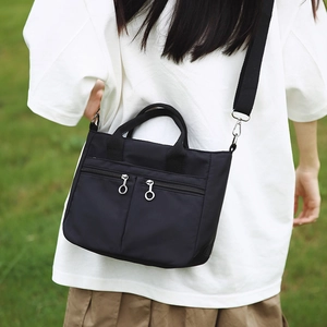 Detail of black nylon crossbody bag with double front zippers and wide woven strap