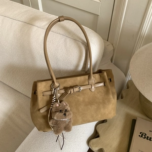 Detail of khaki suede tote bag with decorative straps and cute plush doll pendant