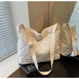 Detail of white quilted tote bag texture and wide strap in natural lighting setup