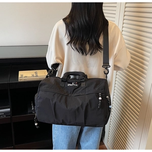 Mannequin portant le grand sac de voyage en nylon noir avec bandoulière et détails latéraux