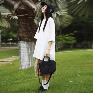 Outdoor view of a black versatile nylon crossbody bag paired with a white oversized T-shirt