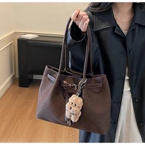 Detailansicht der geflochtenen Ledertasche in Dunkelkaffee mit Plüschanhänger