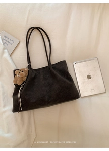 Close-up of matte vintage tote bag with bear charm on soft white fabric background