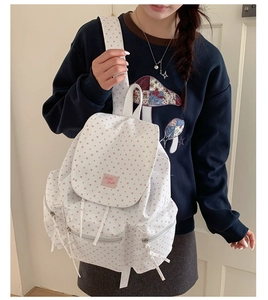 Close-up of white canvas backpack with pink star patterns on a female model