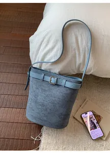 Détail d'un sac seau bleu en faux daim avec boucle métallique sur tapis doux