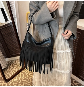 Dettaglio della borsa nera con lunghe nappe e cuciture in materiali misti