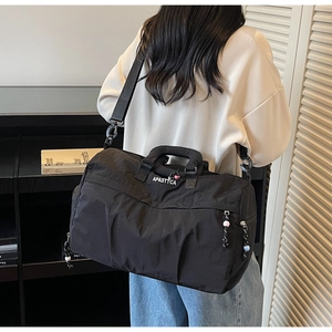 Détail du sac de sport en nylon noir avec lettrage blanc et bandoulière réglable amovible