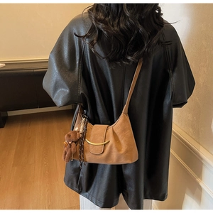 Detail of crescent crossbody bag with golden metal buckle and cute plush bear charm