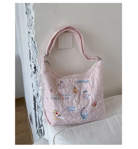 Détail du sac à main matelassé rose avec motifs de cœurs et broderies de chat