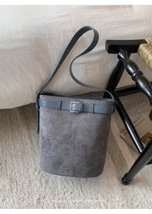 Vue détaillée du sac seau en daim gris avec sangle décorative et boucle argentée