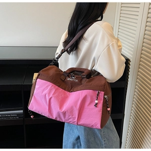 Détail du sac de voyage avec broderie rose, coutures contrastées et bandoulière large