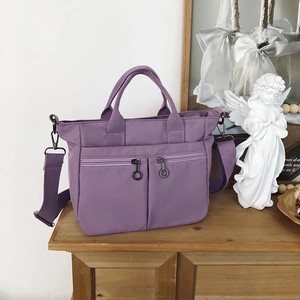 Close-up of purple nylon tote bag featuring dual zipper pockets and reinforced handles