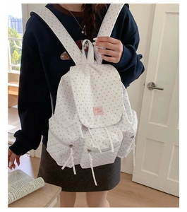 Detail showing white canvas backpack with pink star pattern and durable zippers