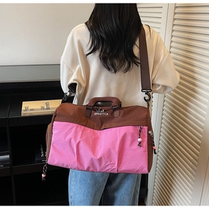Gros plan d'un sac de voyage bicolore marron et rose à grande capacité avec bandoulière