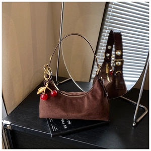 Close-up of brown suede hobo bag with gold hardware and a cute red cherry pendant