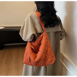 Close-up of orange quilted tote bag with diamond stitching shown on a model