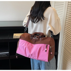 Détail du sac de voyage rose et marron avec poignées renforcées et bandoulière réglable