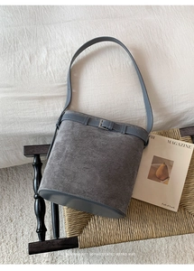 Détail du sac seau en daim gris avec boucle métallique minimaliste et texture premium