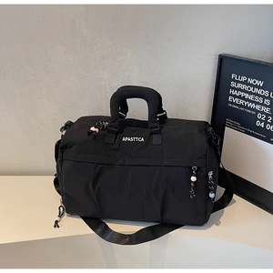 Détail du sac de voyage noir avec doubles poignées et breloques de fermeture éclair colorées