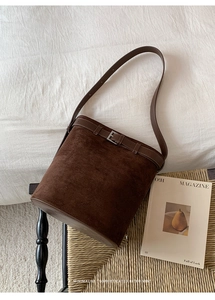 Gros plan sur la texture du sac seau en daim marron café sur une chaise vintage
