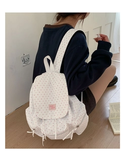 Close-up of a white canvas backpack featuring pink star prints and a K&B Hello woven label
