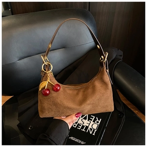 Close-up of brown suede half-moon bag featuring a decorative glitter cherry pendant