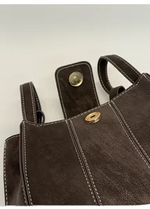 Detail of magnetic snap closure and contrast stitching on vintage faux leather bucket bag