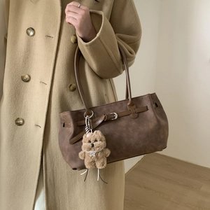 Detail of vintage dark brown suede tote bag with belt buckle and cute plush dog charm